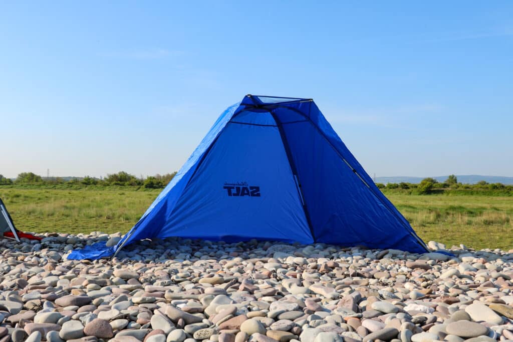 blue fishing shelter on pebble beach in sunshine
