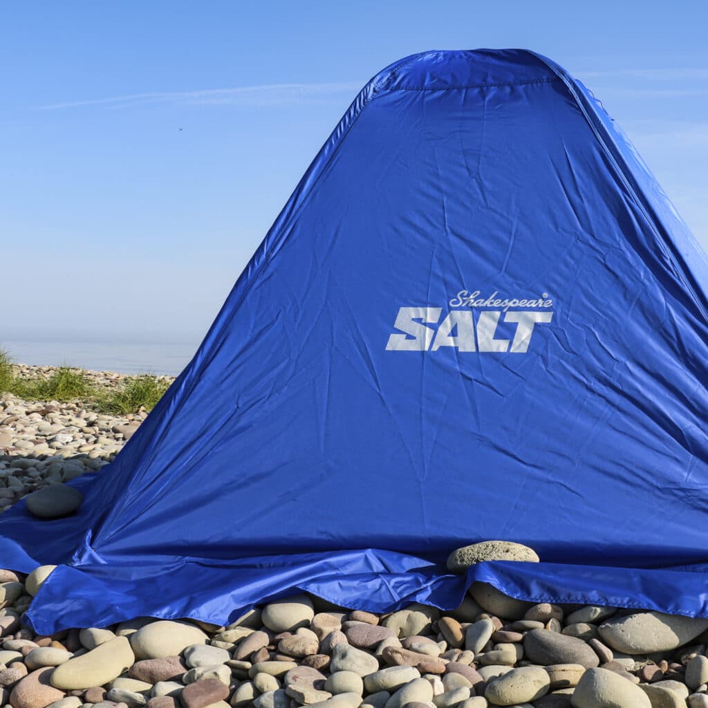 close up of blue beach fishing tent on pebble beach
