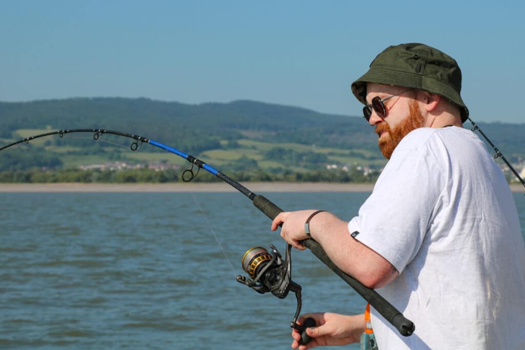 man winding in a fishing rod on a boat
