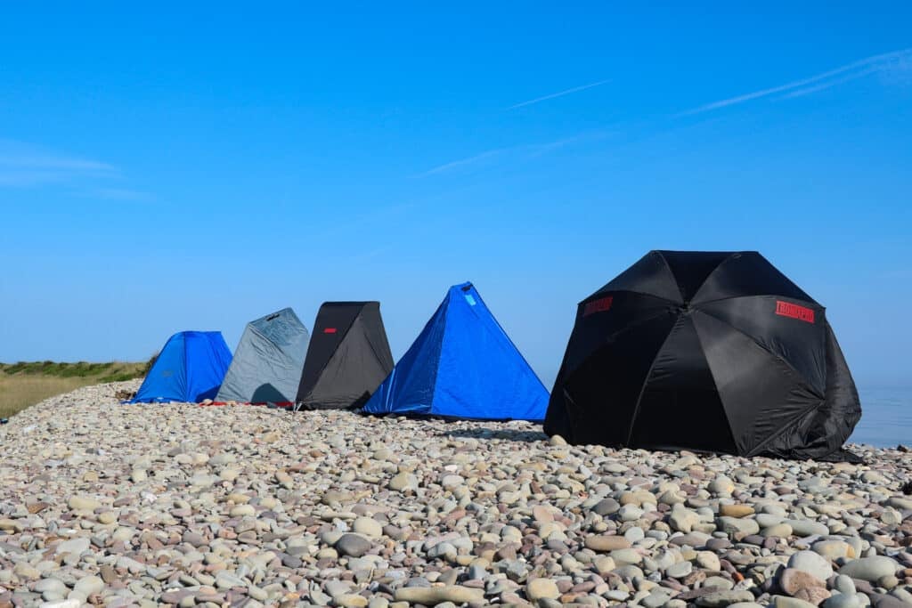 fishing shelters lined up on pebble beach