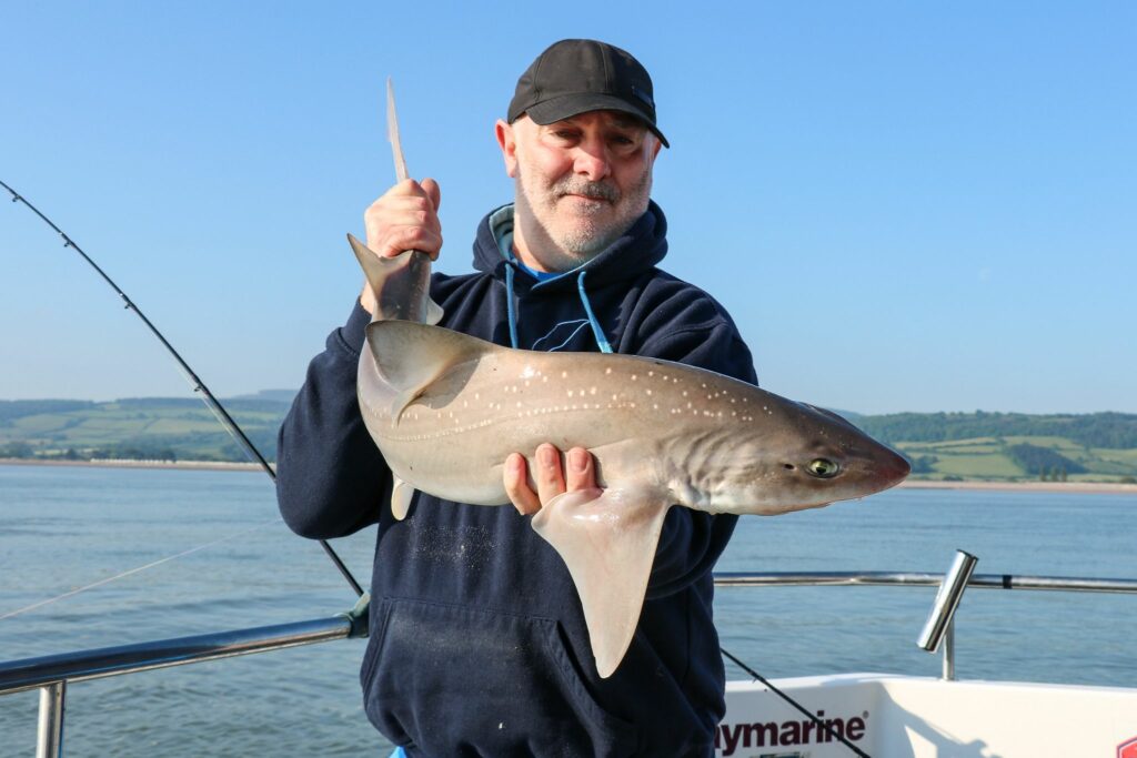 man holding a shark on a boat